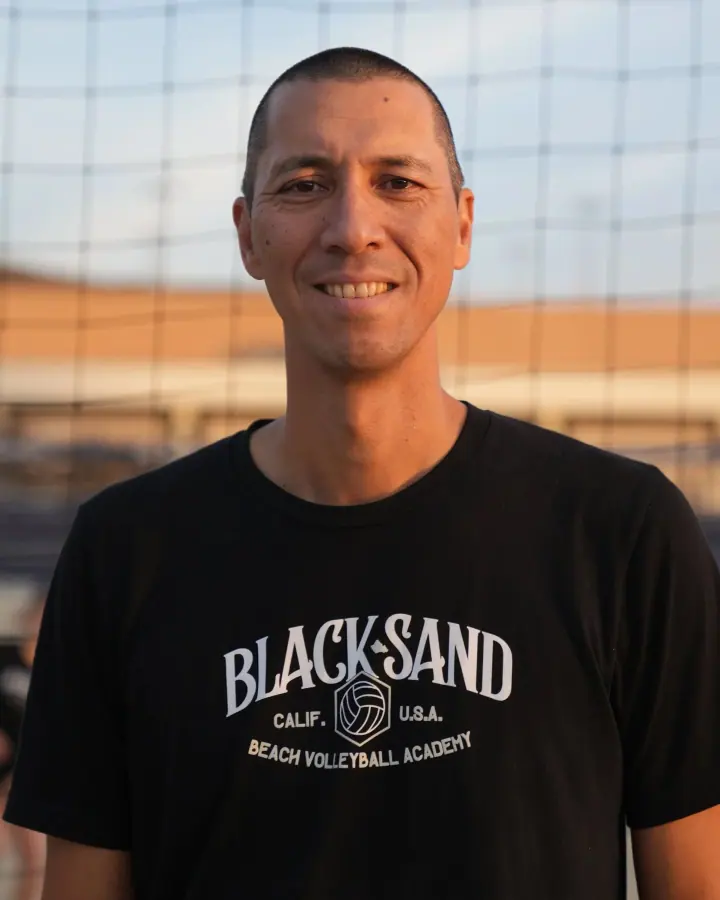 Coach Adam Black on a sand court in a Black Sand shirt