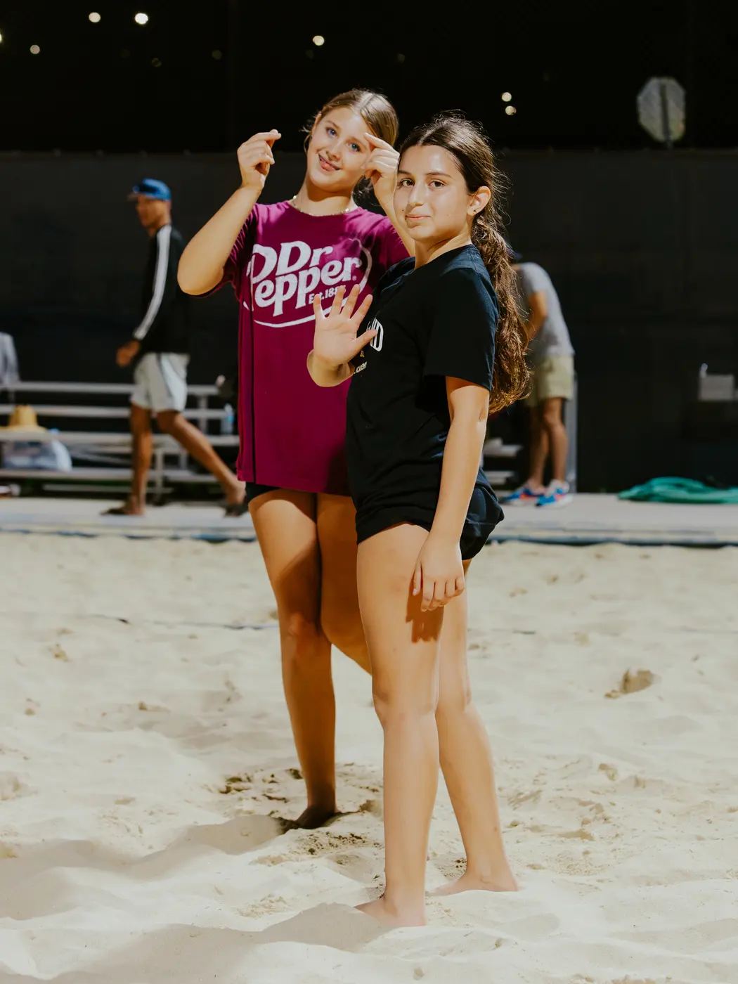 Two players pose together on the sand