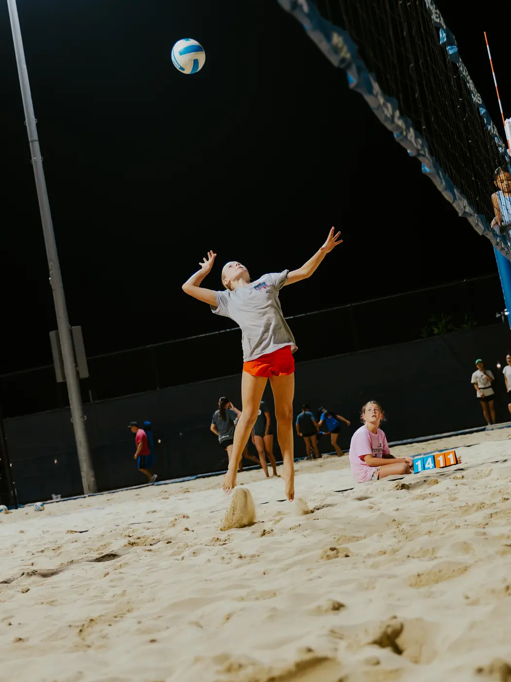 A player tosses to serve under the lights