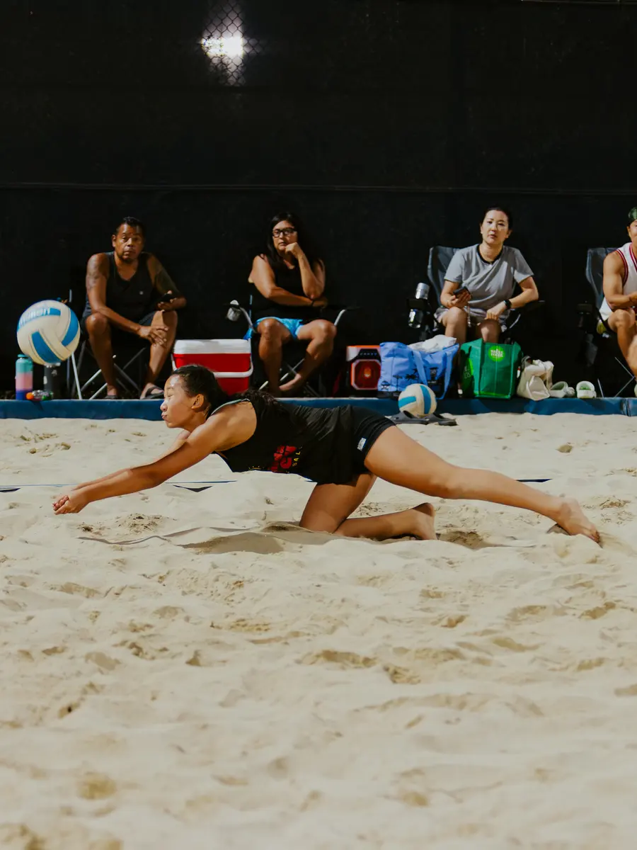 A player dives for a dig during a night match